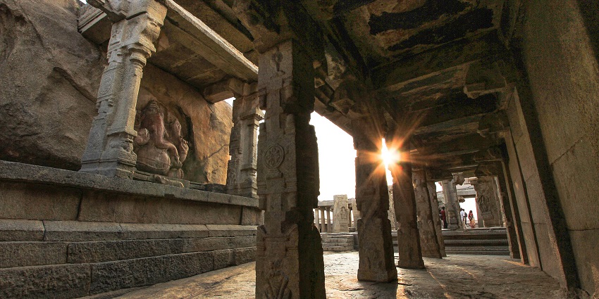 Stone-pillared temple corridor with carved idol and sunlight streaming, one of the best places to visit in Andhra Pradesh in March.