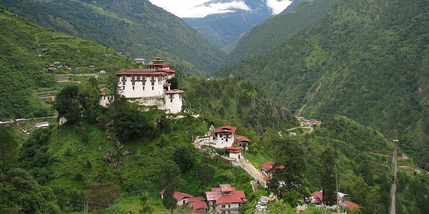 Lhuentse dzong in Bhutan with traditional Buddhist architecture surrounded by green mountains, amongst the best places to visit in Bhutan in July.