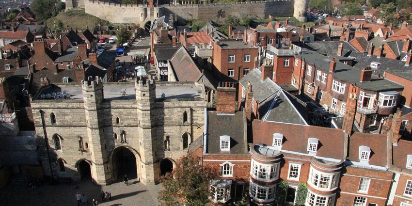 Lincoln Castle with tall buildings of the castle, reddish buildings and people entering