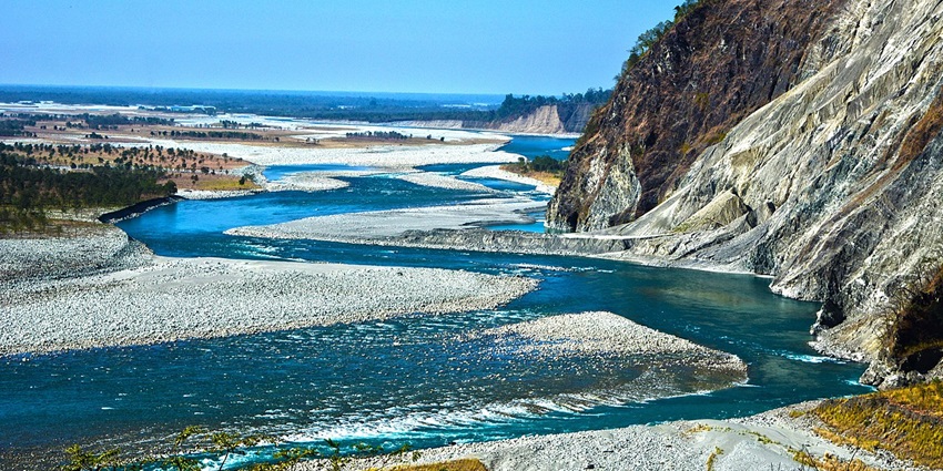 Lohit River from above with bright blue water body, rocks on the shore and green trees