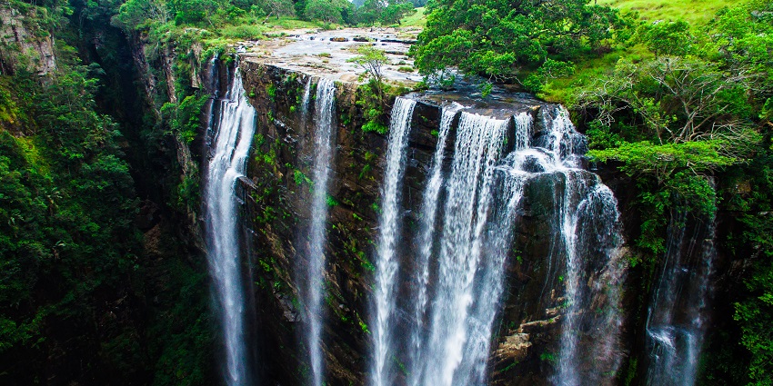 Magwa Falls with multiple waterfalls flowing on the rocky surface, surrounded by lush greenery, one of the most beautiful hidden places in South Africa.