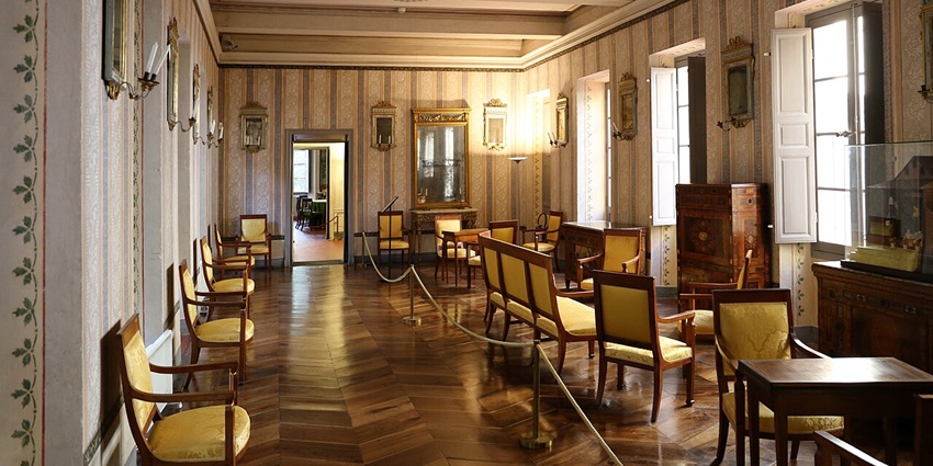 Interior of the Maison Bonaparte museum with old preserved wooden furniture and frames.
