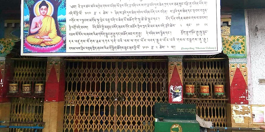 Prayer wheels lined up against a red wall outside the monastery, one of the best places to visit in Delhi in October.