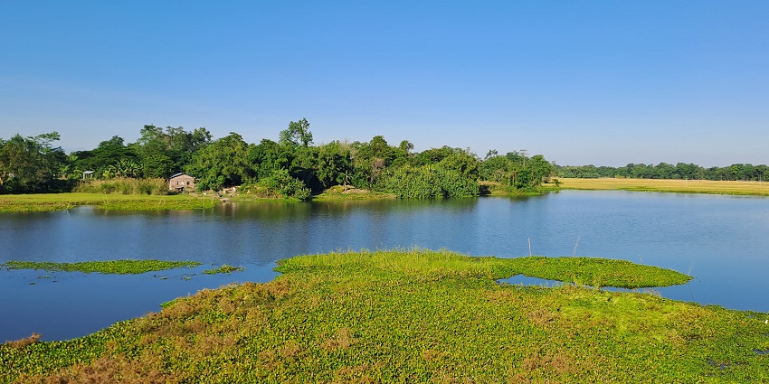 Doriya Ghat in Majuli island with a large water body of the river, sandy shore and green trees