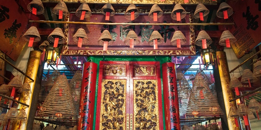 Ornate altar inside Man Mo Temple with red lanterns and incense coils hanging above, one of the historical places in Hong Kong.
