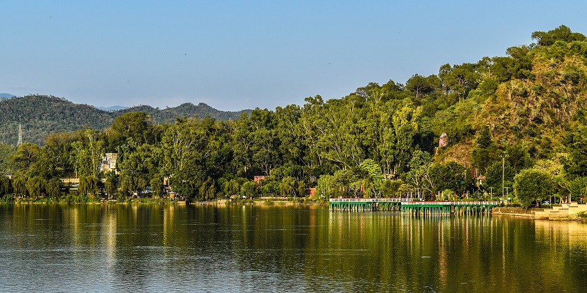 Tranquil Mansar Lake with tree-lined shoreline reflecting the surrounding greenery