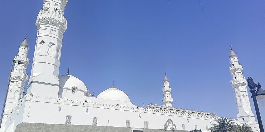 Masjid Quba with detailed architecture on minarets, palm trees, one of the historical places in Saudi Arabia.

