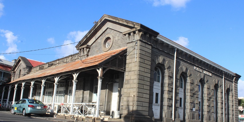 Historic Mauritius Postal Museum building with arched windows under a clear blue sky.