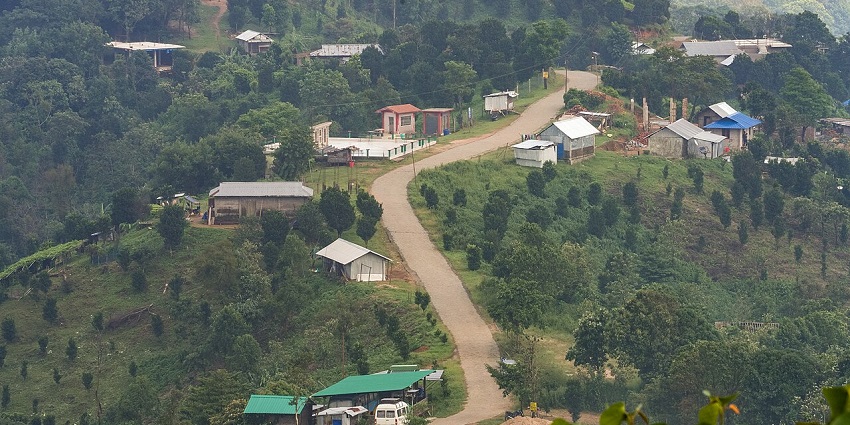Village in Meghalaya with a street in the middle, greenery, multiple houses and buildings.