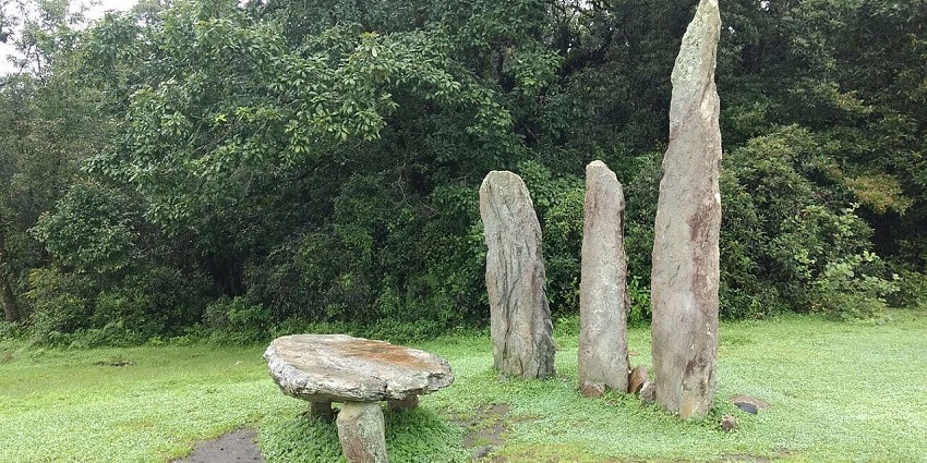 Unique rock monoliths on Mawphlang sacred grove with green grass and grove trees.