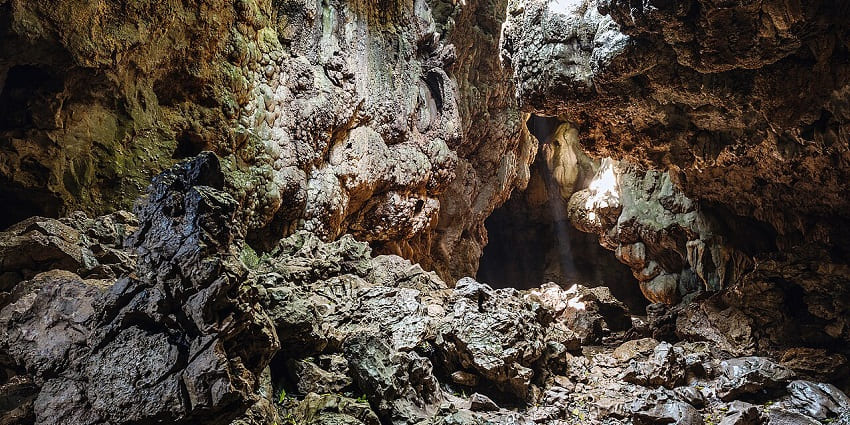 Mawsmai cave in Meghalaya with surface of the cave walls and sunrays hitting the walls.
