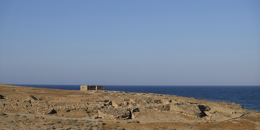 A stunning view of an archaeological site with its ruins along the vast stretch of blue sea.