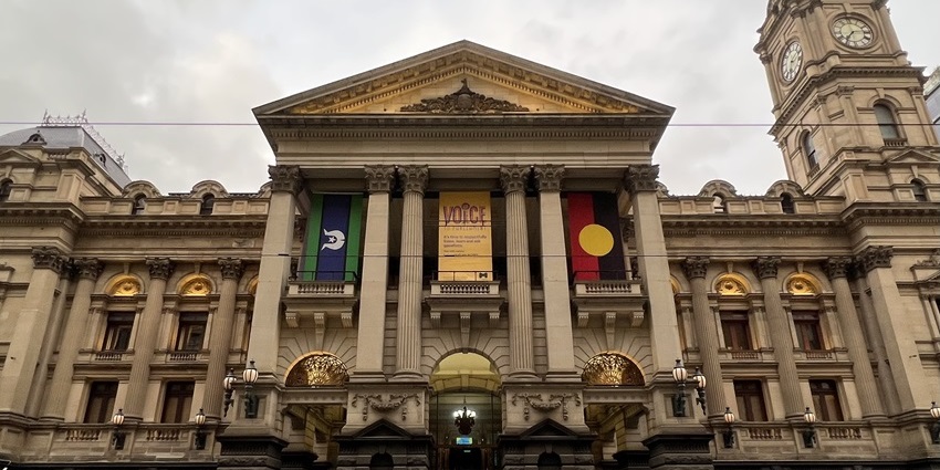 Clock tower and façade of Melbourne Town Hall against a blue sky.