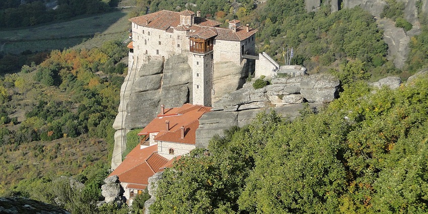 The Monastery of Rousanou in Meteora, Greece, is perched atop a cliff surrounded by forest, one of the best historical places in Greece.