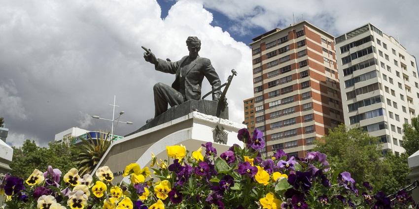 Monument to Eduardo Abaroa with a vibrant flower garden and a blue sky filled with clouds.