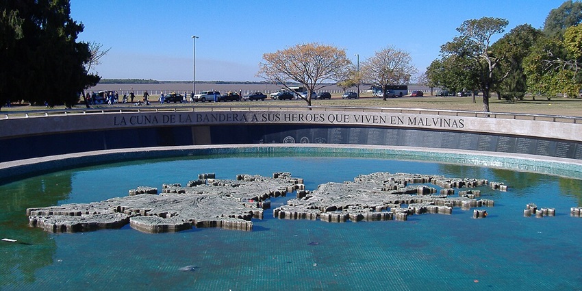 Monumento a los Caidos en Malvinas with a small water body and cars in the background.