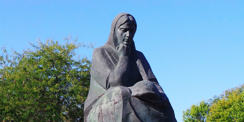 Motherland Monument in Kyiv with a raised sword and shield, with a black sculpture in front.