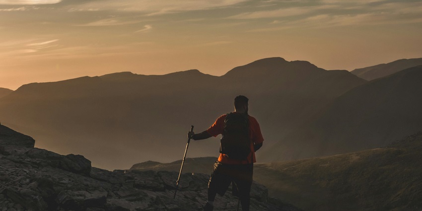 A man hiking Mount Sinai at sunrise, with a scenic view and vibrant sky.