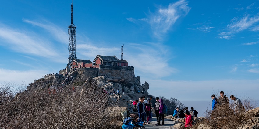 Jade Emperor Peak on Mount Taishan with a tall network tower, buildings and people visiting