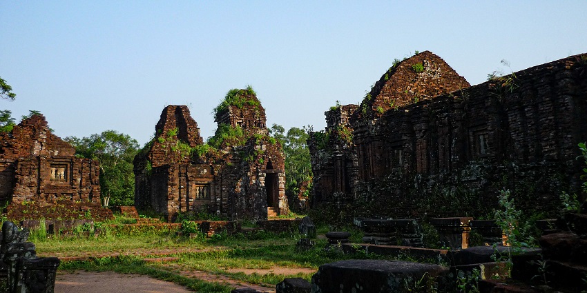 Ruins of a red-brick Cham temple at My Son Sanctuary, surrounded by lush greenery.