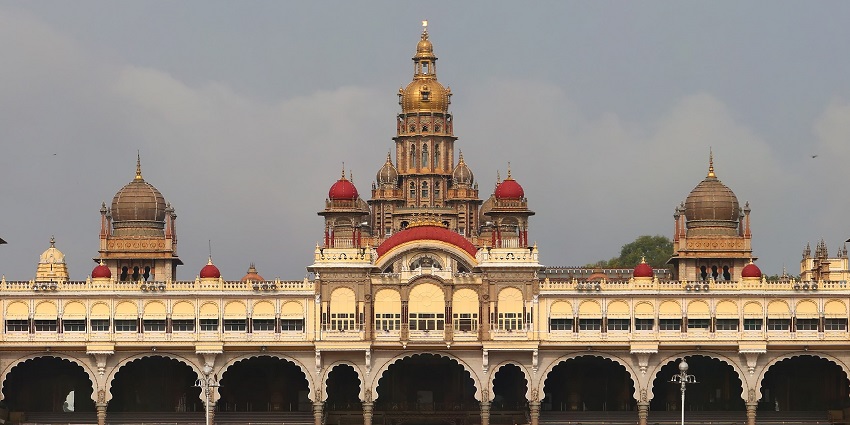 Majestic palace with domes and arches under a cloudy sky, one of the best places to visit in Karnataka in February.