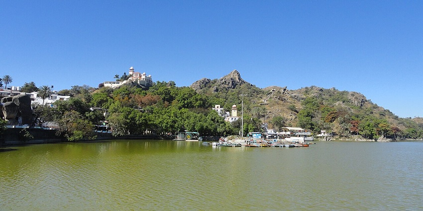 Nakki Lake at Mount Abu with distant mountains, multiple boats parked and buildings.