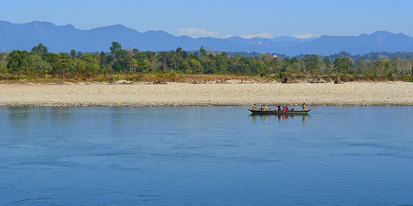 Nameri National Park with people on a boat on Jiabhoroli River and rocky shoreline