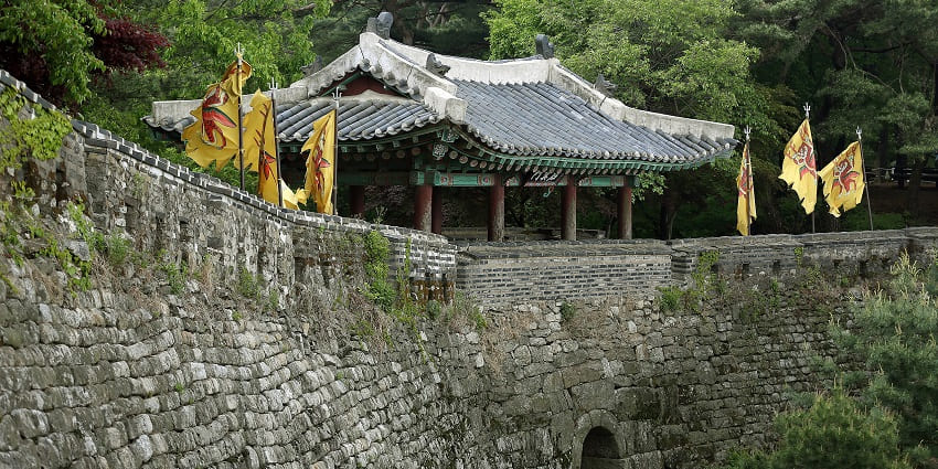 Namhansanseong Fortress with flags on the border of old brick wall of the fortress