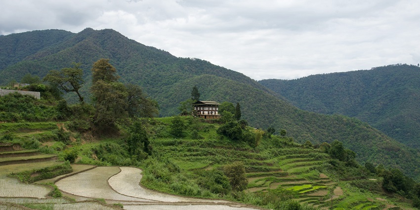 Wooden house on green field near mountains with white clouds and bright blue sky