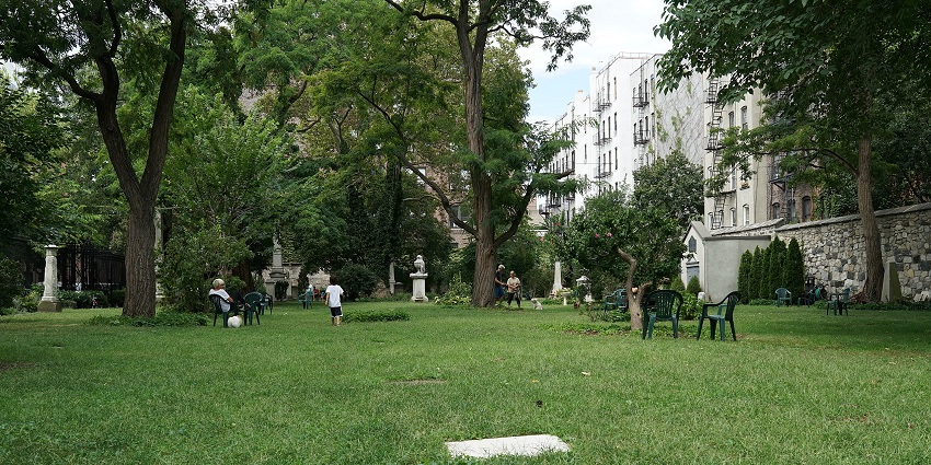 New York City marble cemetery with multiple distant white statues and a person on a chair