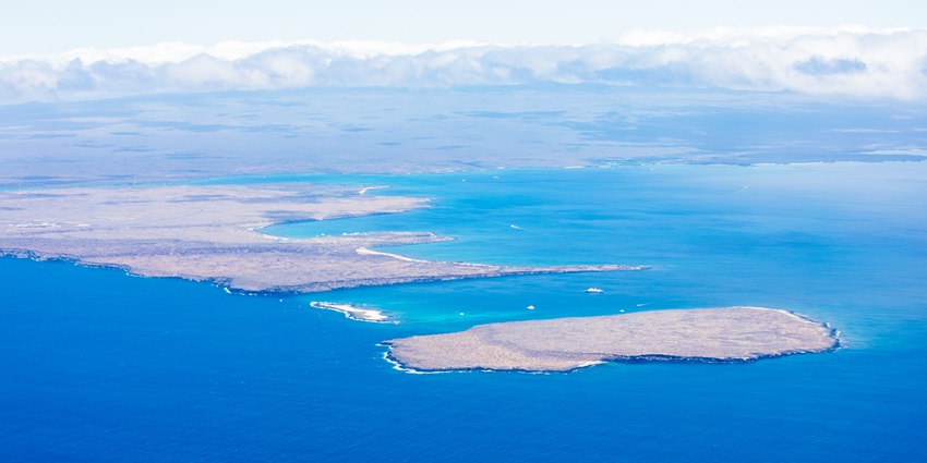 Aerial view of a rugged island coastline with blue bays, surrounded by deep blue ocean