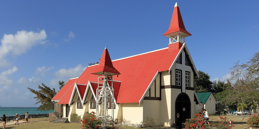 Red-roofed Notre Dame Auxiliatrice chapel overlooking the blue sea at Cap Malheureux.