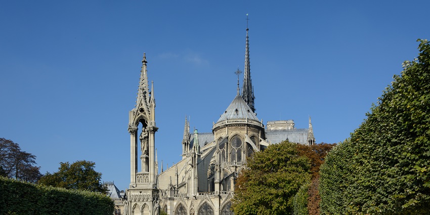 A Gothic cathedral with a spire and buttresses, seen from a garden with trees and flowers, is one of the best historical places in France.