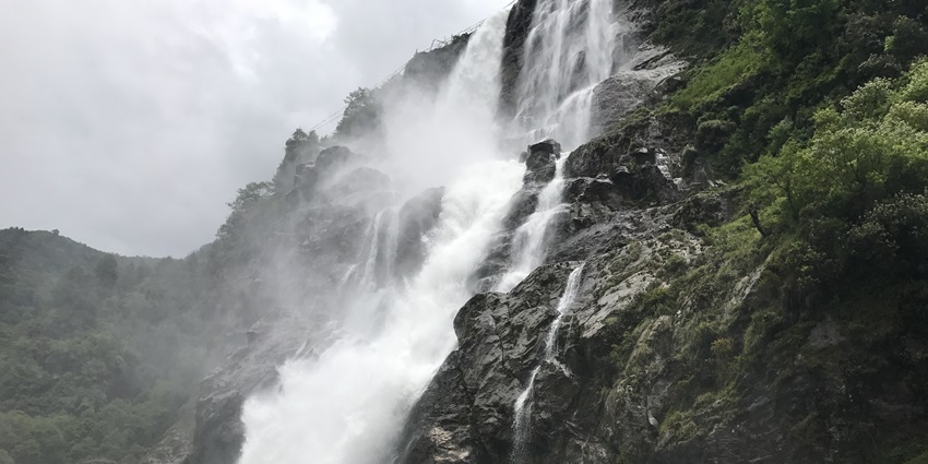 Nuranang falls in Tawang, with water flowing on the rocky surface and a cloudy blue sky