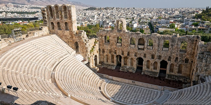 A well-preserved Roman stone theatre with semi-circular seating and a grand stage.
