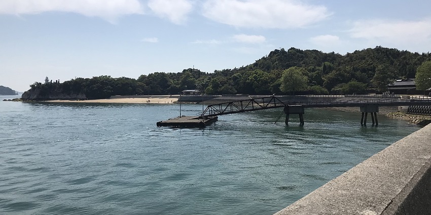 Pier number one of Okunoshima Island with a distant beach and lush greenery in the back
