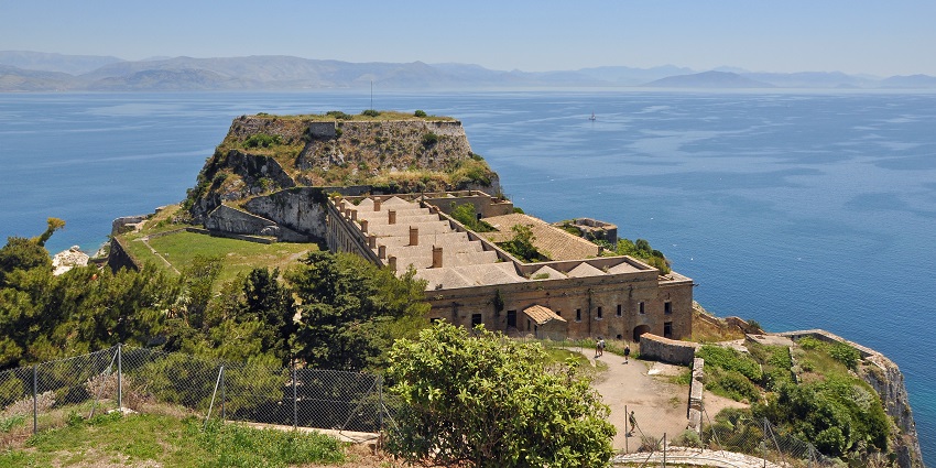 Old Venetian fortress on Corfu island overlooking the blue Ionian Sea and mountains, one of the historical places in Corfu.