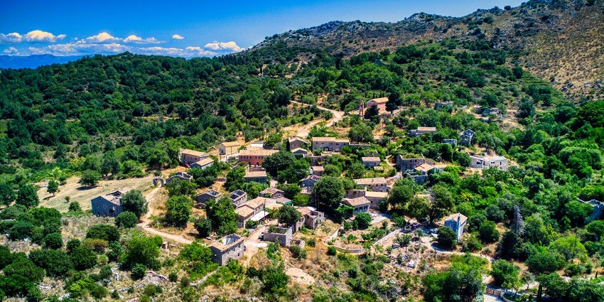 Peak of the Mount Pantokrator with multiple colourful houses and lush greenery.