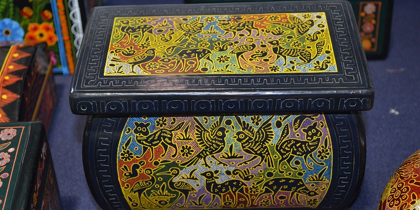 Delicately painted lacquered boxes and trays from Olinalá showcasing floral patterns.