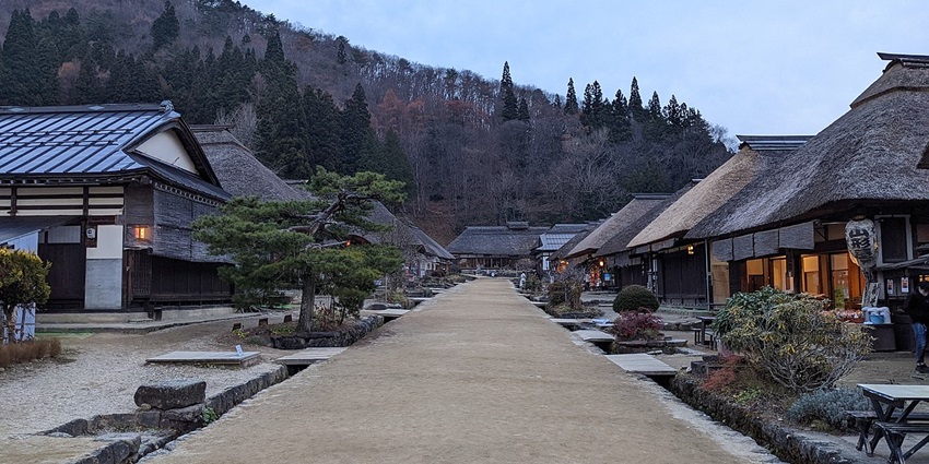 A street of Ouchi Juku village with traditional Japanese houses, lamps hanging and small trees