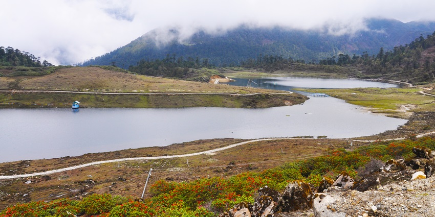 P.T. Tso Lake with a large water body, a small boat near the lake and green shores