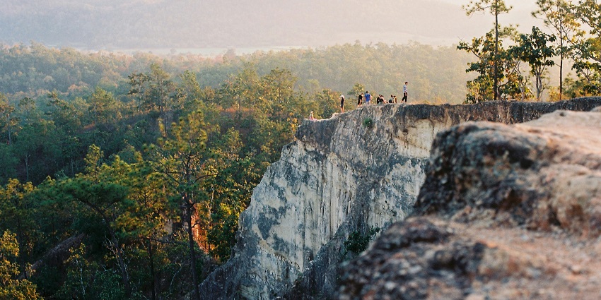 Pai with dense green trees, people walking on the trail, and mountains, one of the places to visit in Thailand in January.