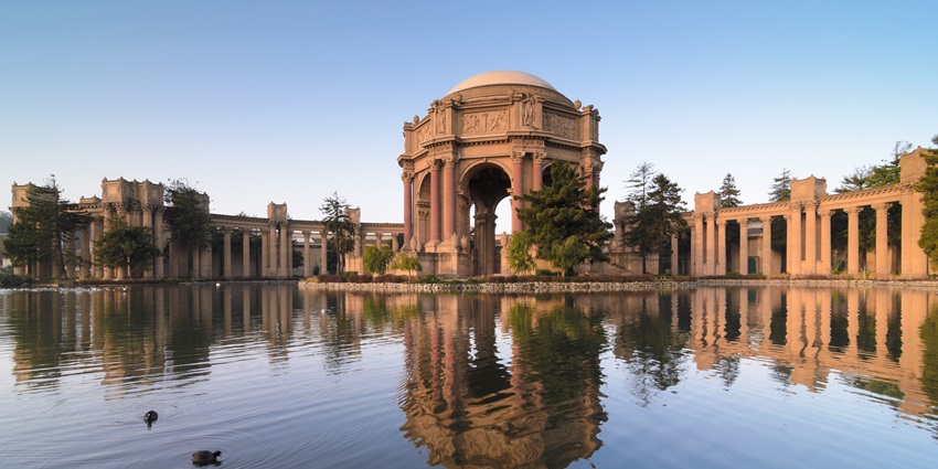 Reflection of the domed rotunda and colonnades on a still pond at sunset in San Francisco