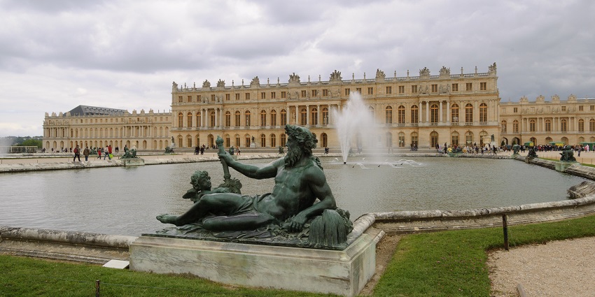 Ornate golden gates and grand palace facade of the Palace of Versailles.