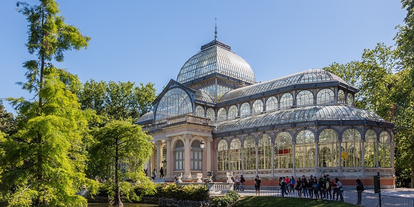 Palacio de Cristal with glass architecture, people visiting the palace and green trees