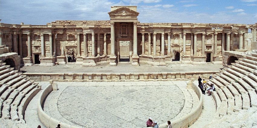 Palmyra theatre with old broken architecture, people sitting on the steps, one of the historical places in Syria.