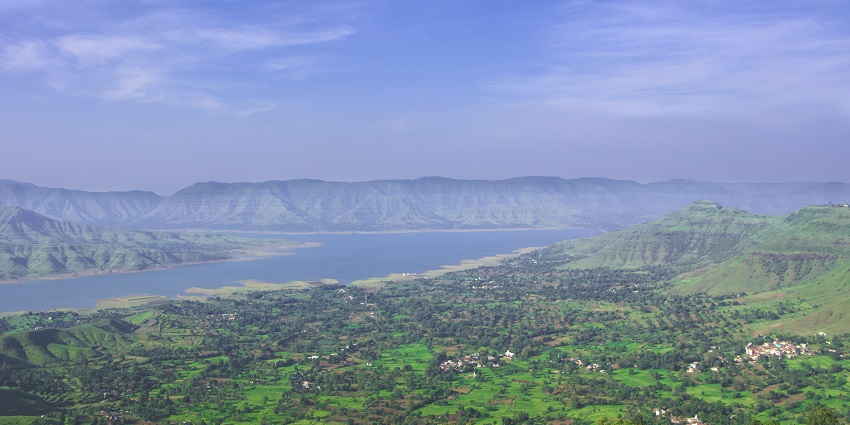 Verdant green hills under cloudy skies near Pune, a summer destination for nature lovers.