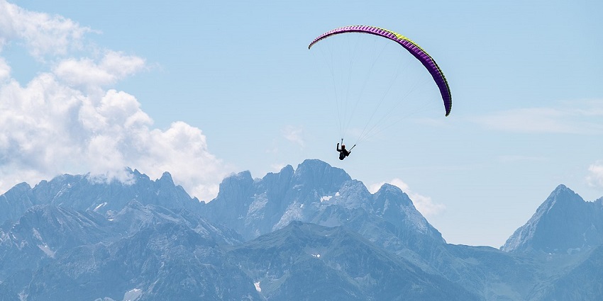 Paraglider flying high over dramatic Dolomite mountain scenery.