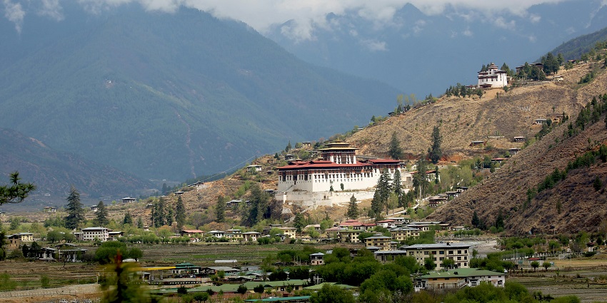 Paro valley in Bhutan with distant small houses, monasteries and mountains, one of the top places to visit in Bhutan in August.