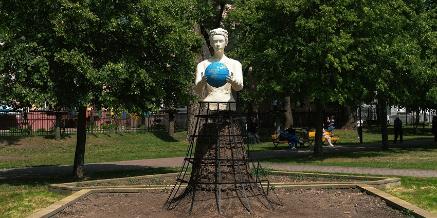 Peace park with a white detailed sculpture holding a globe and people at a distance.
